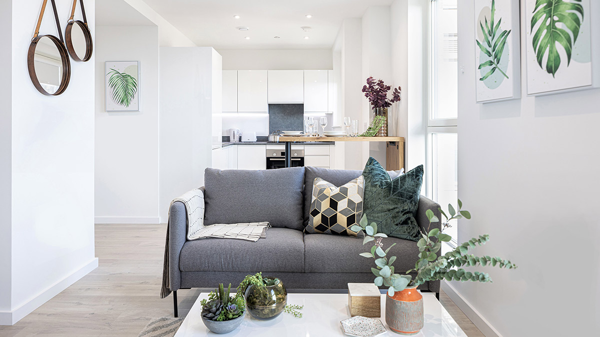 Open-plan living area with gray sofa and white kitchen