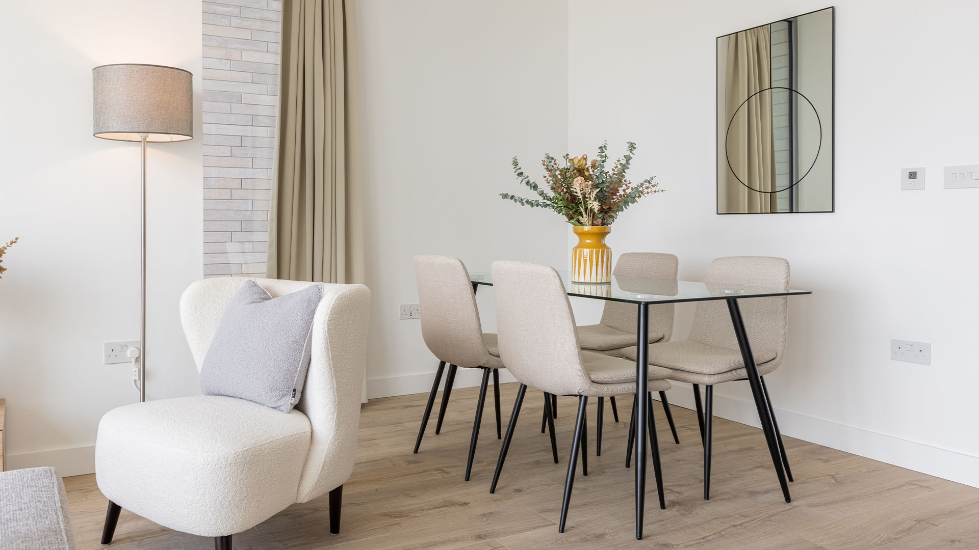 Modern dining area with a glass table, beige chairs, and cozy armchair of Valencia Tower