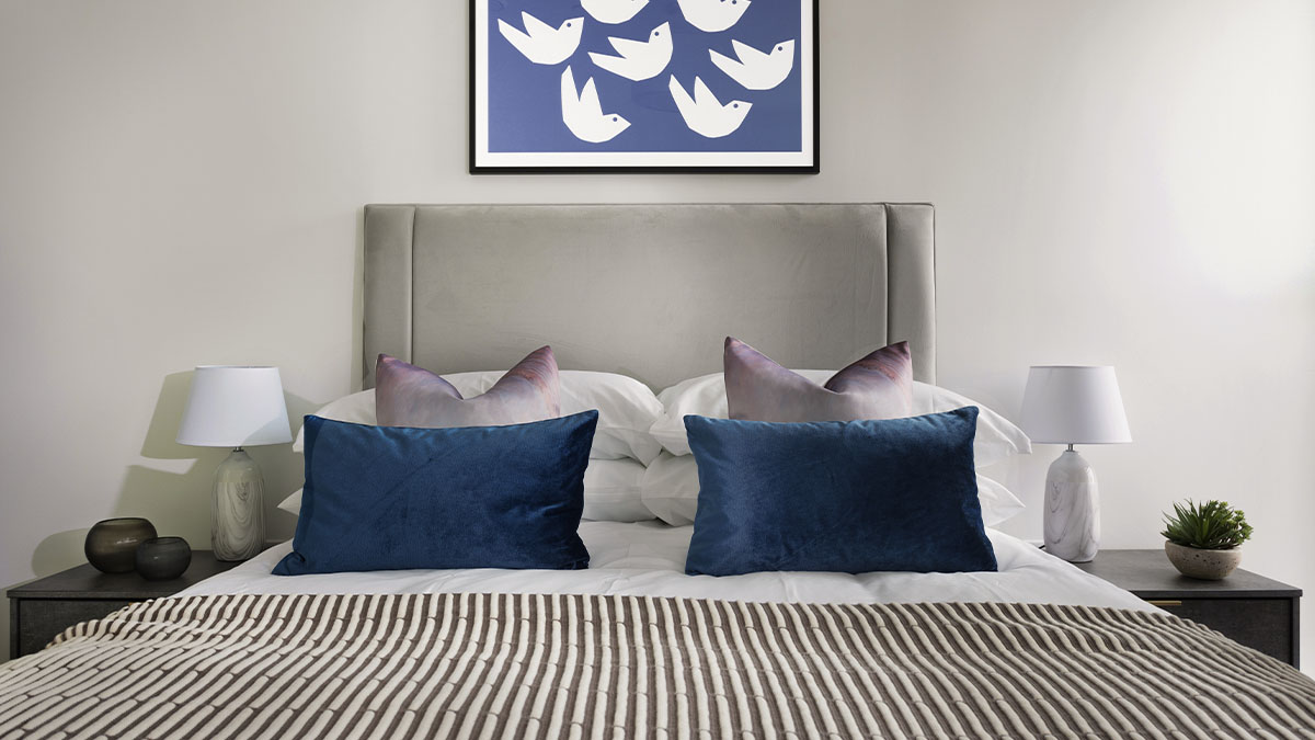 Bedroom with blue cushion and artwork on wall