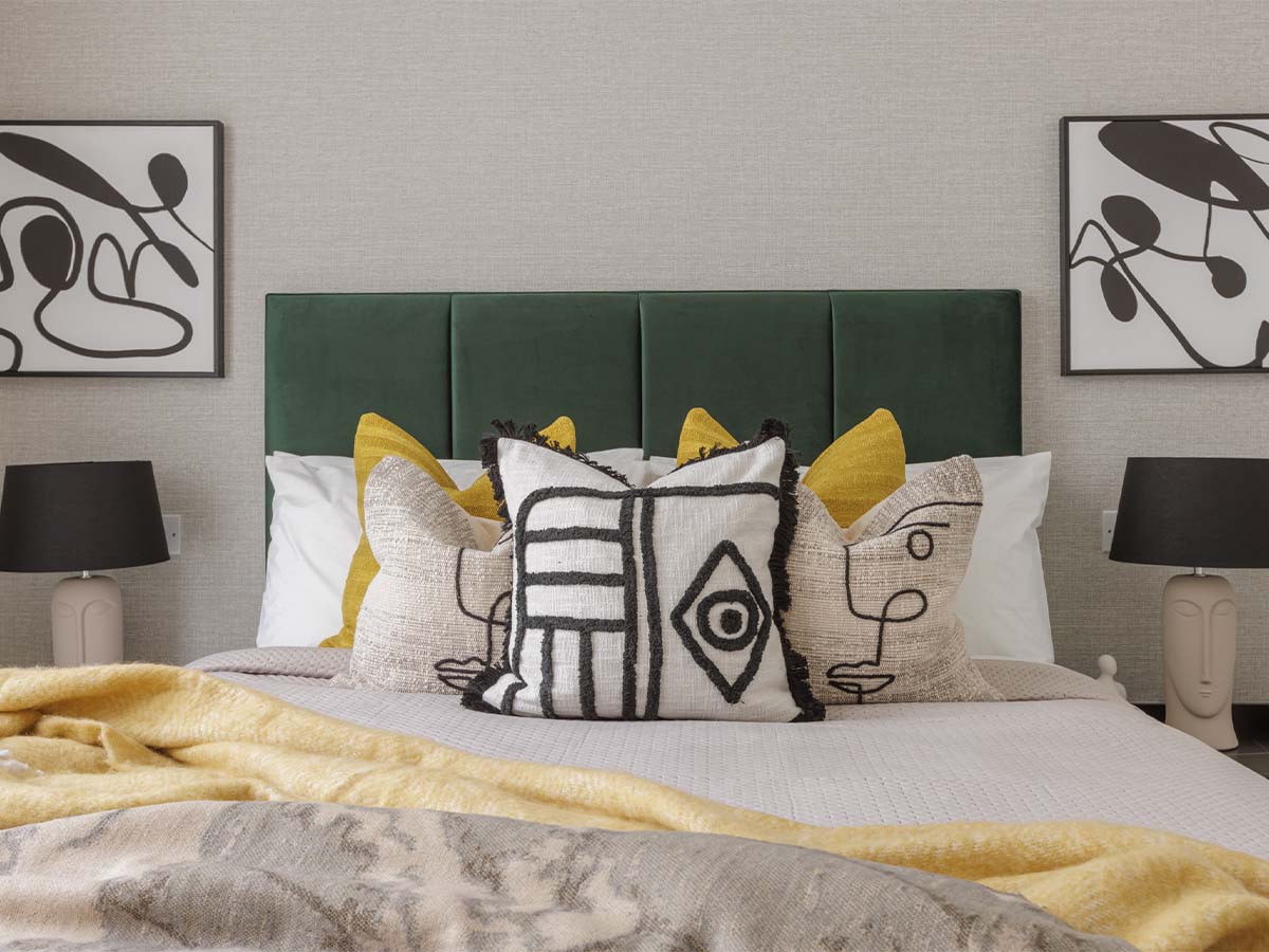 Bedroom with white and yellow pillows and artwork of Harcourt Gardens