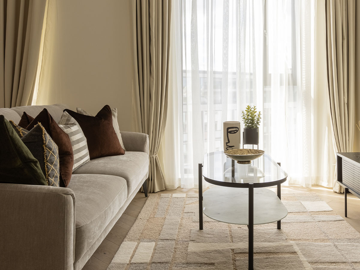 Bright living room with beige sofa, glass coffee table, and natural light of Pembridge Gardens, Notting Hill