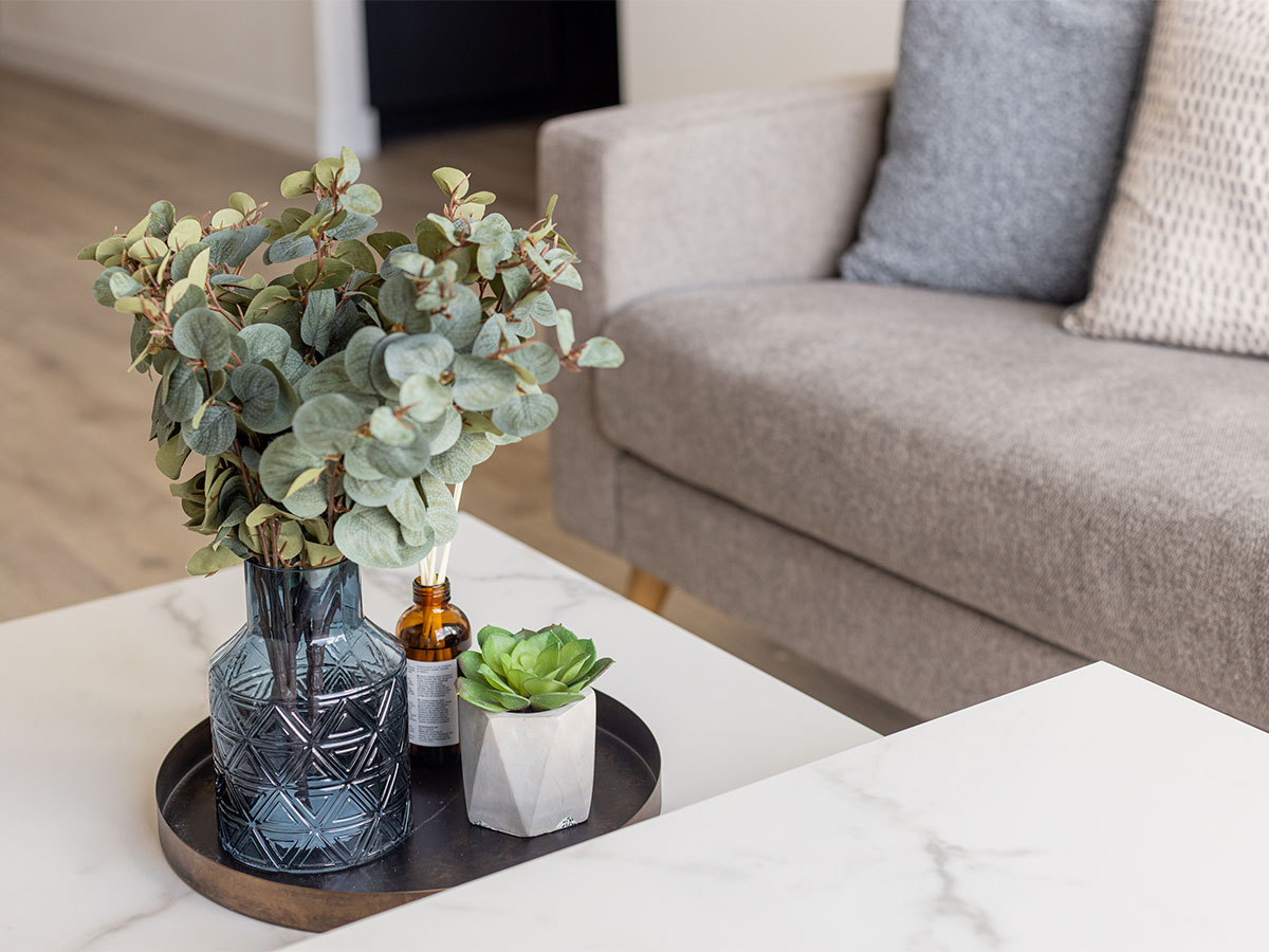 Glass vase with eucalyptus, succulent, and diffuser on a coffee table. of Valencia Tower