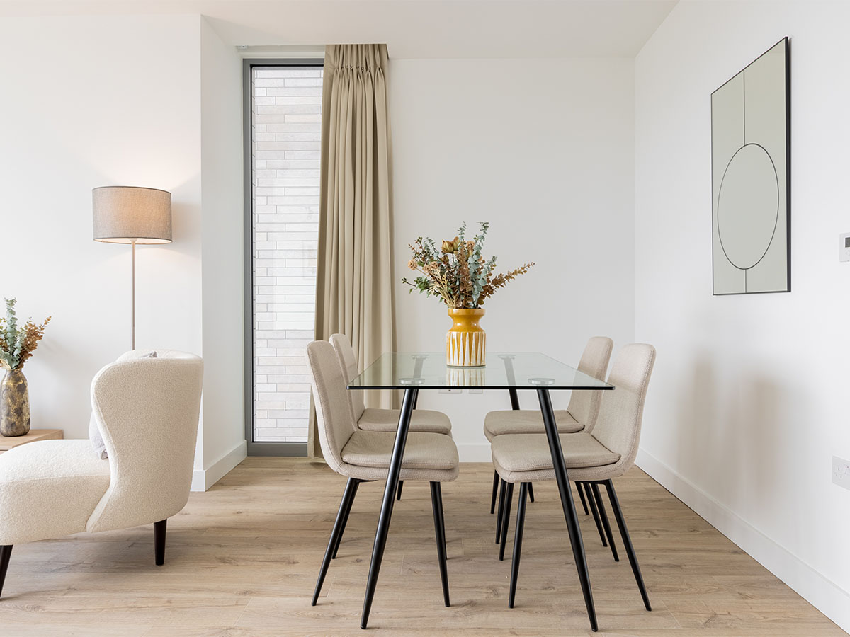 Modern dining area with a glass table, beige chairs, and window dressing of Valencia Tower