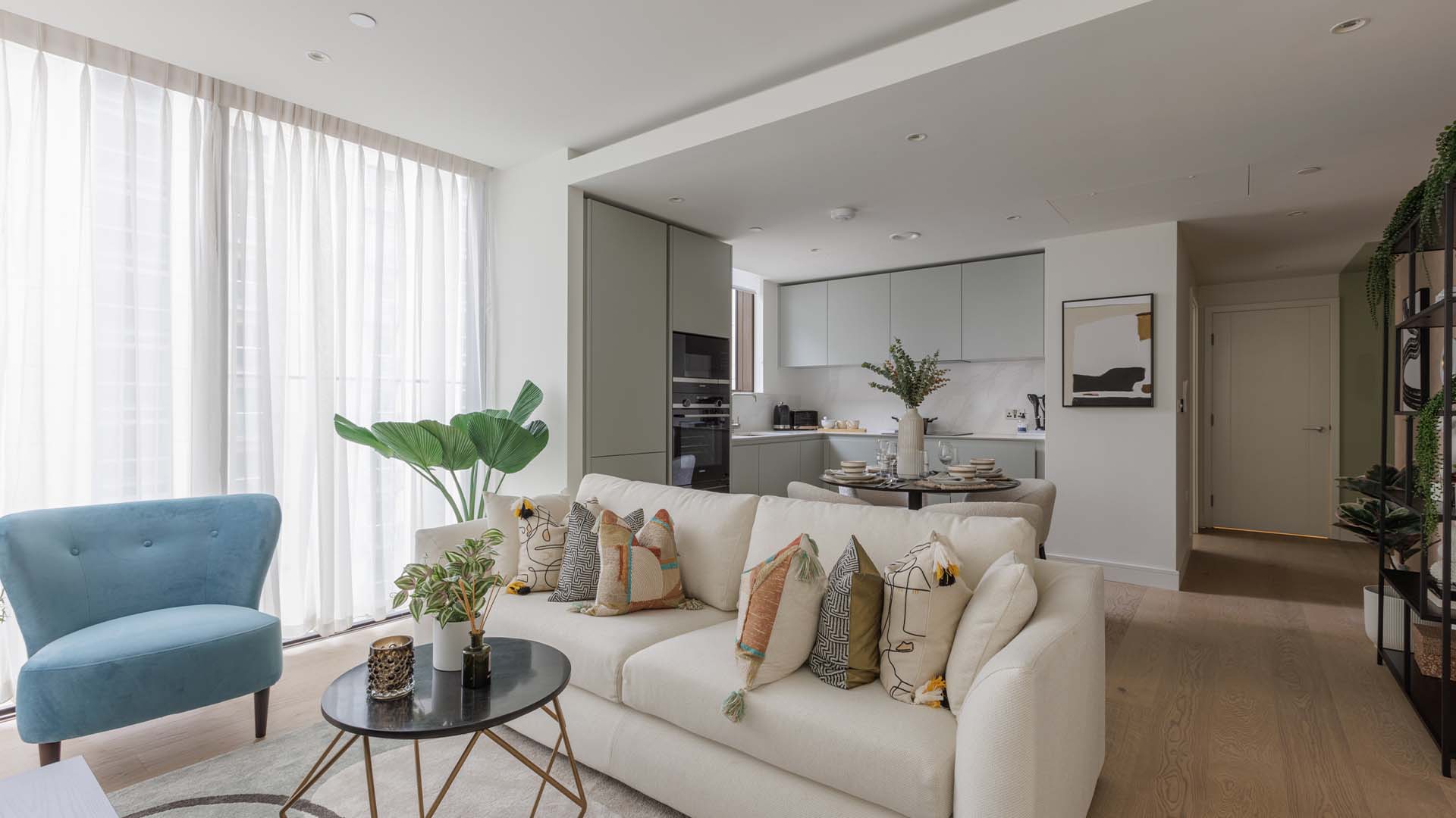 Modern open-plan living room with cozy sofa, blue chair, and green accents of Harcourt Gardens-31