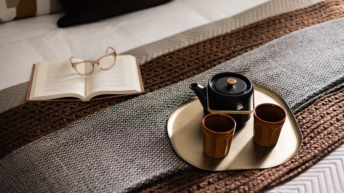 A cozy bedroom corner with a book, glasses, and a tea set of Verdica show flats