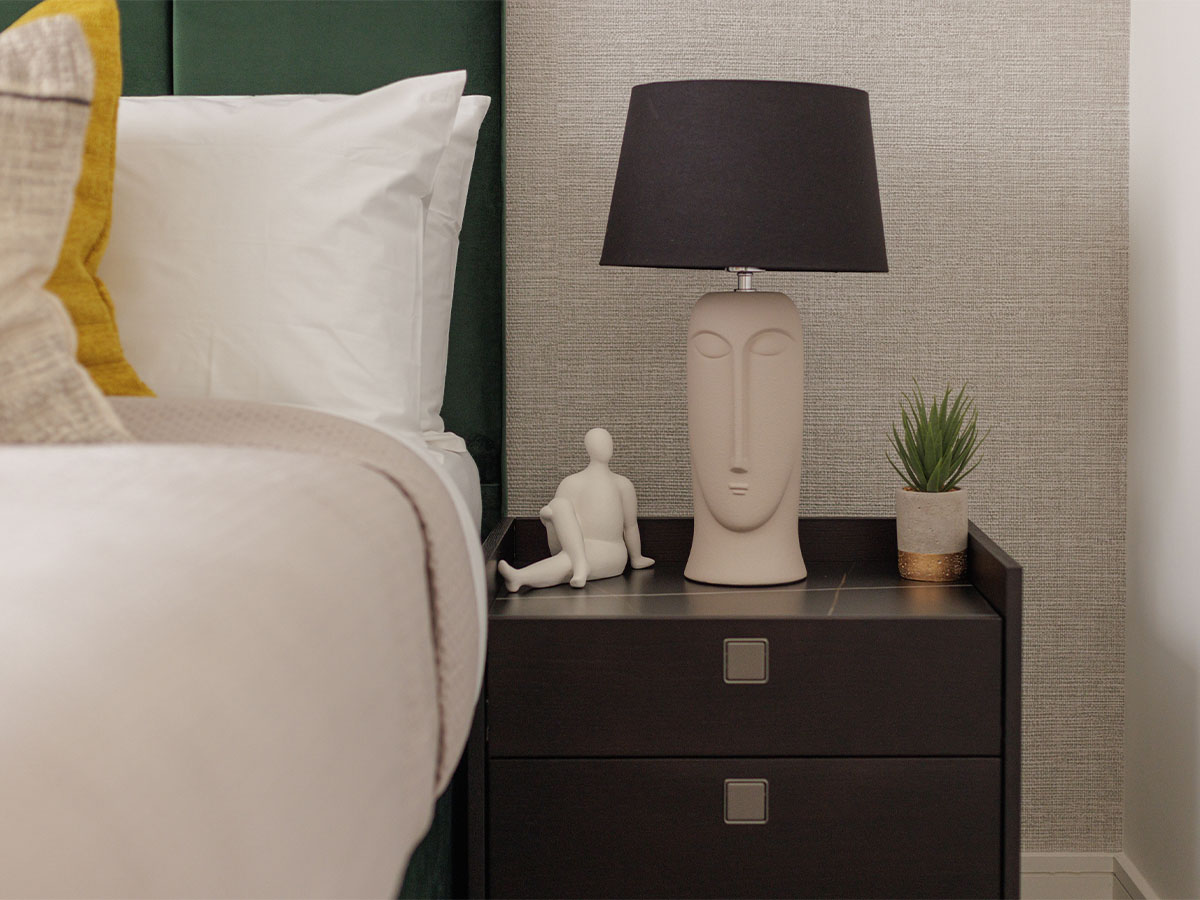 Face-shaped lamp with black shade on nightstand of Harcourt Gardens