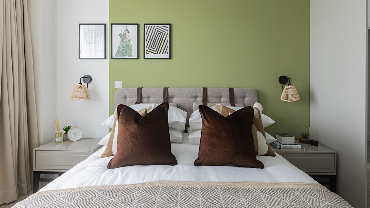 Modern bedroom with green accent wall, cozy bed, and artwork