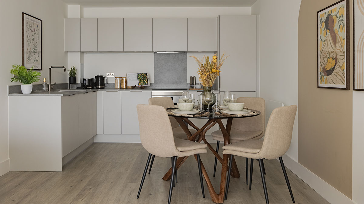 Modern kitchen and dining room with white cabinets, glass table, and artwork