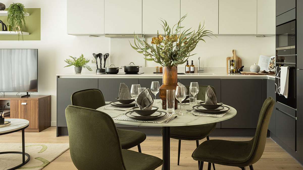 kitchen and dining area with a round table and green chairs of Verdica show flats