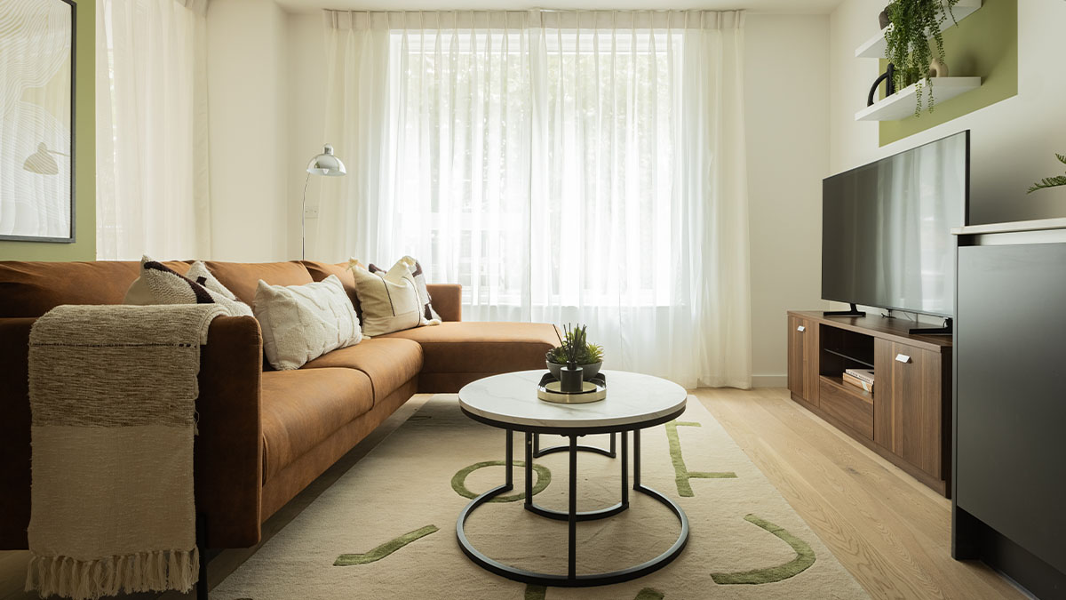 living room with a brown leather sectional sofa, coffee table and TV of Verdica show flats