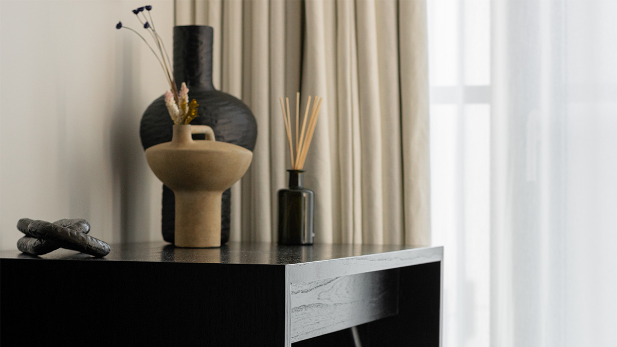 Black side table with vases, reeds, and decorative accents