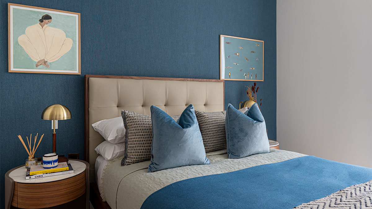 Cozy bedroom with blue accent wall & tufted headboard 