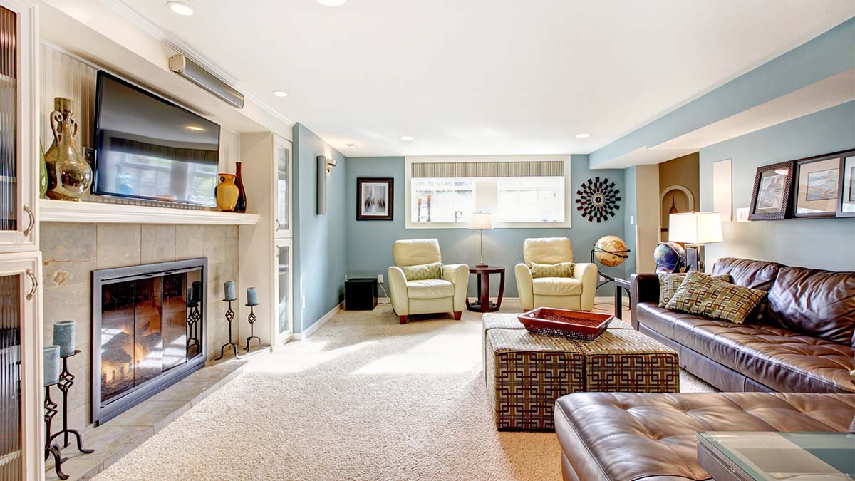 Cozy living room with fireplace, mounted TV, leather sectional sofa, cream armchairs, and light blue walls