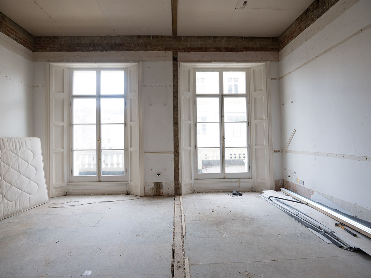 Empty room with two windows and construction debris