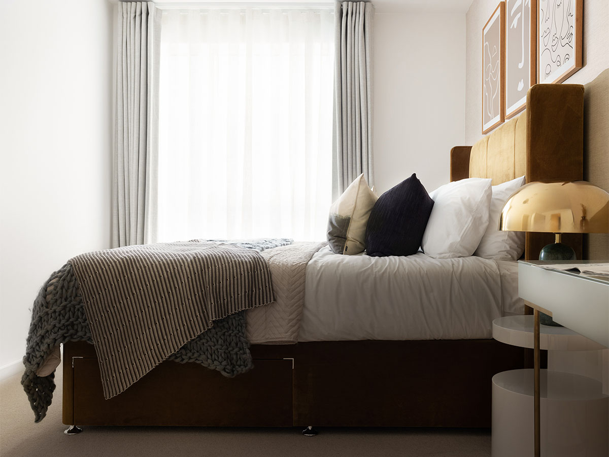 Modern bedroom with gold headboard and striped blanket