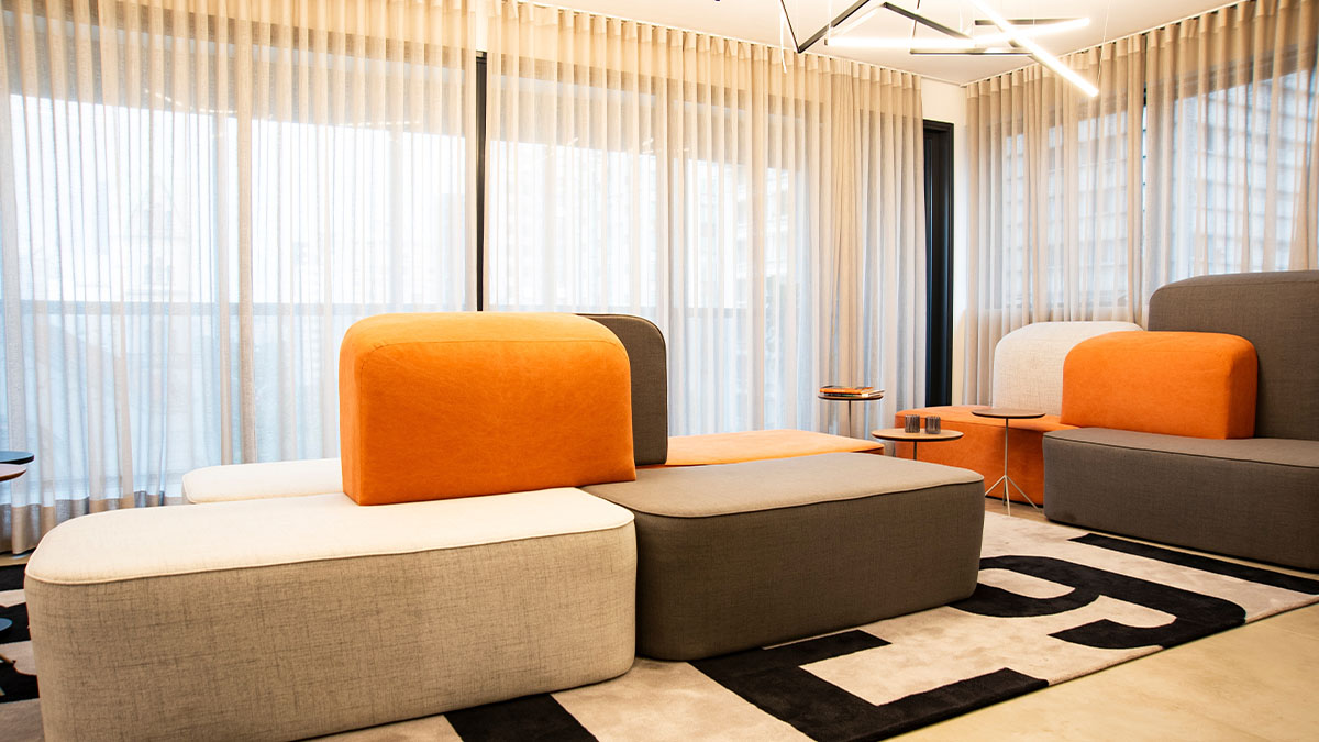 Modern lounge area with modular seating in orange, cream, and gray colors on geometric black and white rug